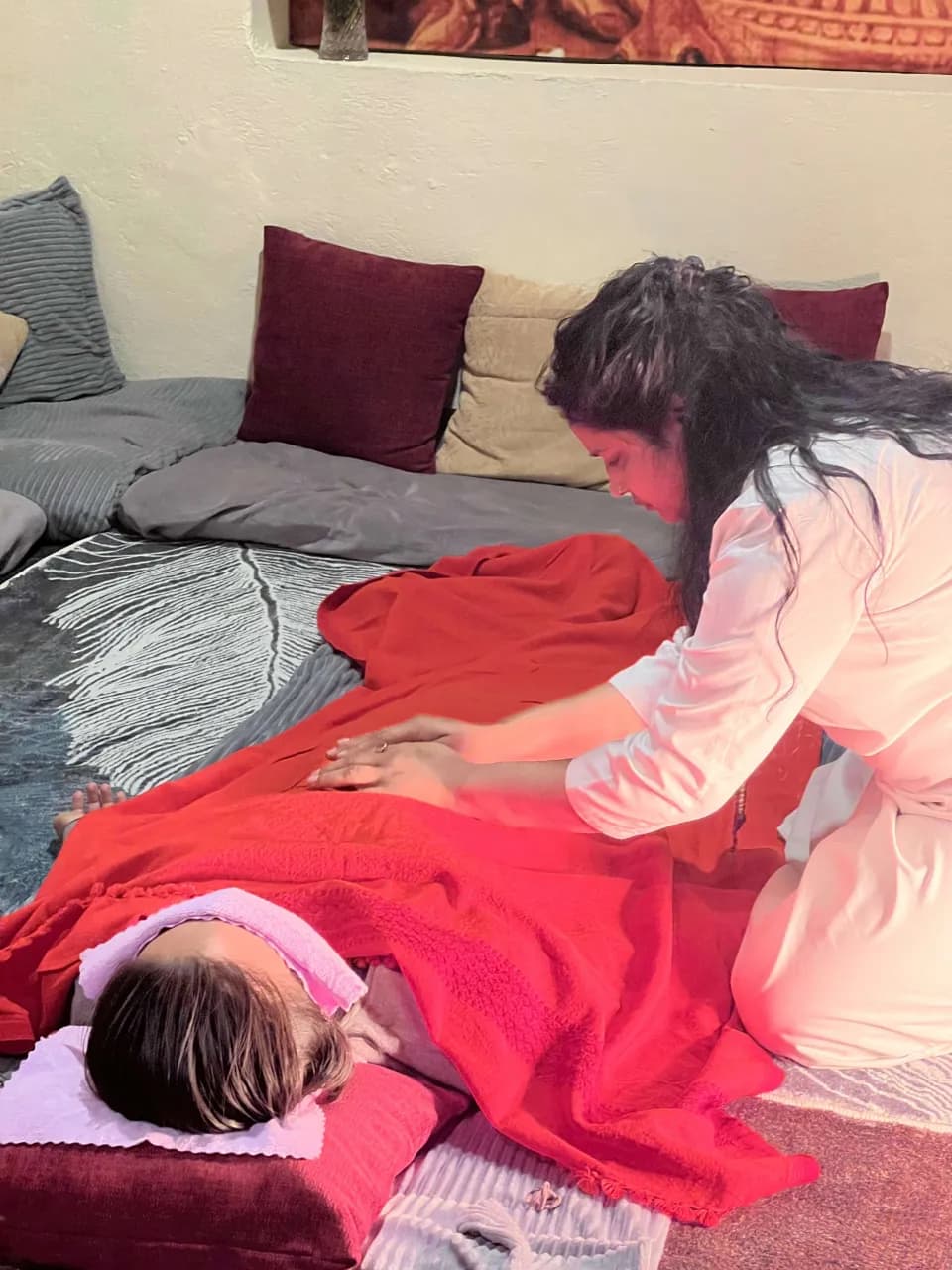 A Reiki practitioner treating a guest lying under a red blanket at Jivan Parivartan, Kathmandu